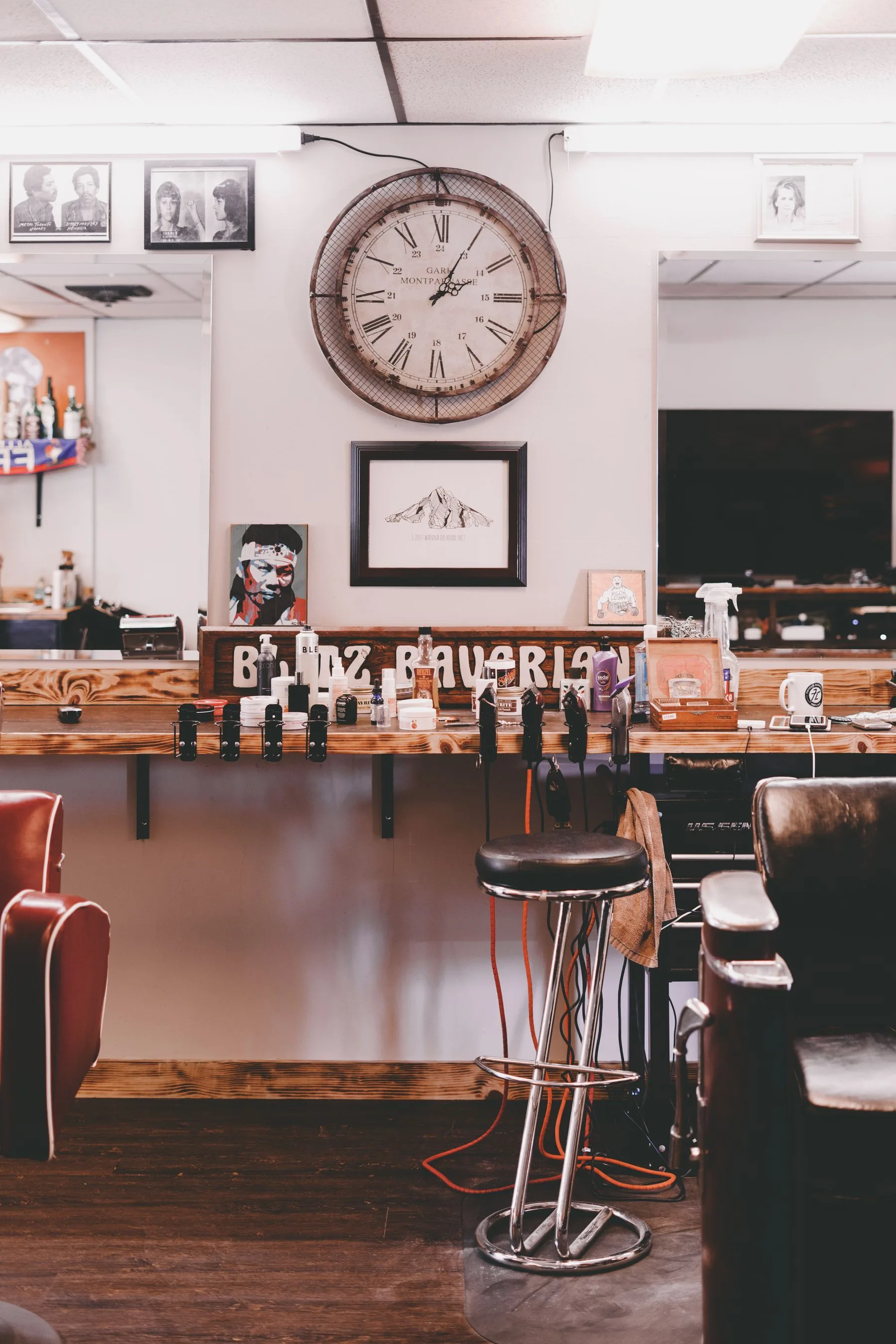 Area kerja barbershop dengan cermin dan jam dinding.